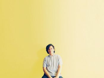 Full length of young man standing against yellow background