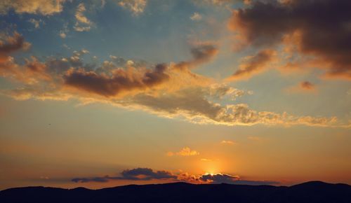 Scenic view of dramatic sky over silhouette landscape