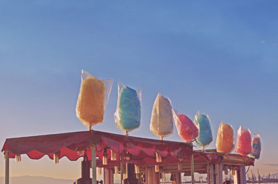 Low angle view of multi colored umbrellas against clear blue sky