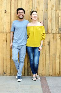 Portrait of cheerful young couple standing against wall