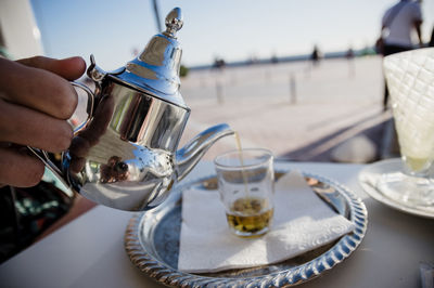 Cropped hand of woman holding drink on table