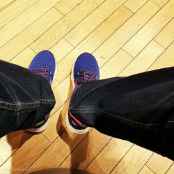 Low section of person wearing shoes on hardwood floor