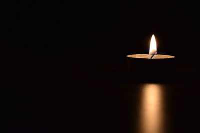 Close-up of lit candle in darkroom