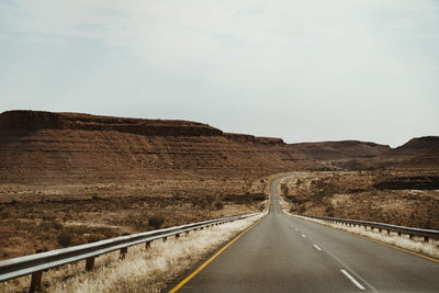 Road leading towards mountain against sky