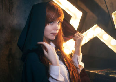 Close-up of young woman standing in illuminated building