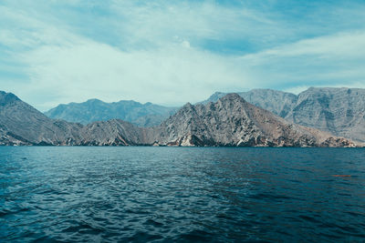 Scenic view of sea by mountains against sky