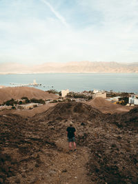 Rear view of man standing on mountain against sky