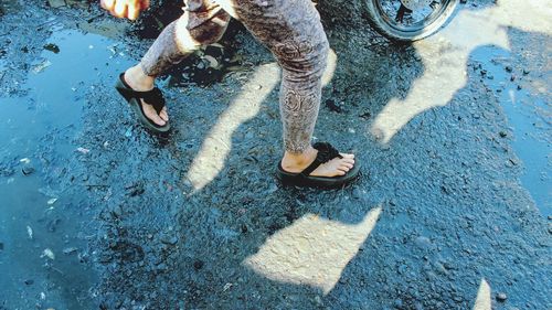 Low section of woman walking on wet street