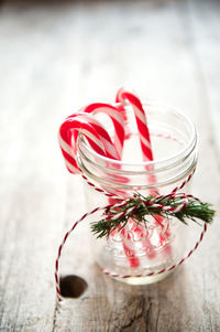 Candy canes in glass container on wooden table