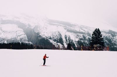 Full length of man skiing on snowy landscape against snowcapped mountain