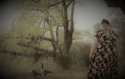 Woman standing by tree in forest