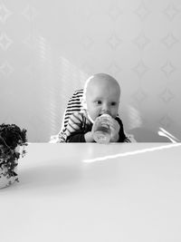 Cute baby drinking from bottle at home