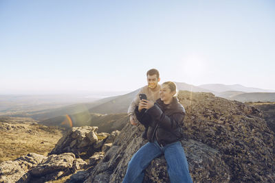 Rear view of men on mountain against clear sky