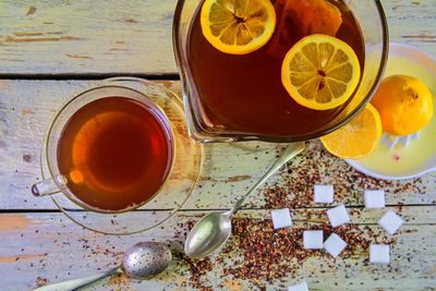 Black tea, a cup of black tea, manual squeezer with lemons. a jug of black tea and cubes of sugar