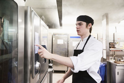 Male chef student operating microwave oven at cooking school