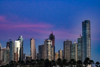 Modern buildings in city against blue sky