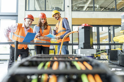 Enineers in factory examining work machine