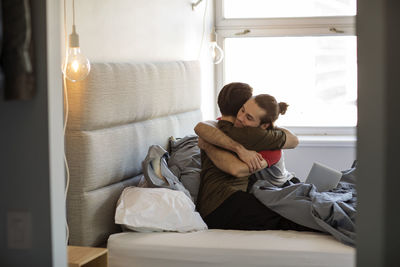 Homosexual couple embracing on bed at home