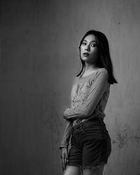 Portrait of woman standing against wall