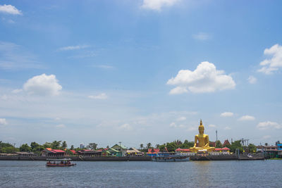 Scenic view of river by buildings against sky