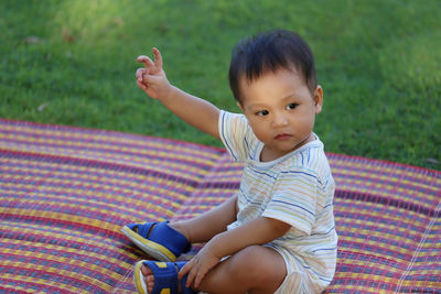 Cute baby boy sitting on mat in park