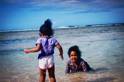 Portrait of siblings playing in water at beach