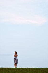 Full length of girl standing on field against sky