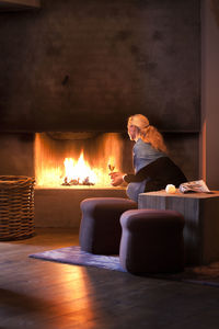 Woman sitting with wineglass and looking at fireplace