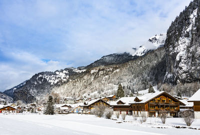 Snow covered houses and mountains against sky