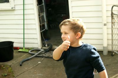 Boy looking away while gesturing thumbs up
