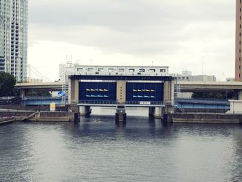 Bridge over river in city against sky