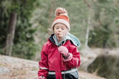 Young girl eating marshmallows by a campfire in the forest in sweden