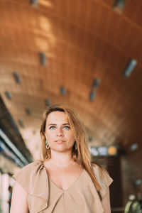 Portrait of young woman standing against building