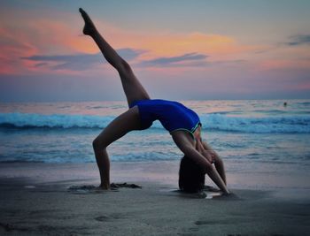 Full length of woman at beach against sky during sunset