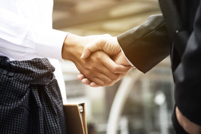 Midsection of business people giving handshake at office