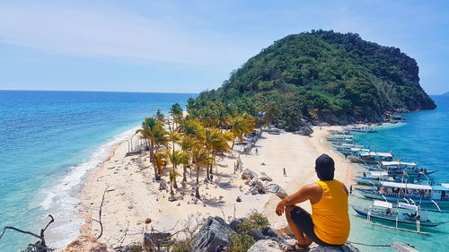 Rear view of man looking at sea against sky