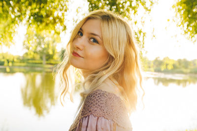 Portrait of young woman standing against lake
