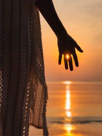 Close-up of silhouetted hand against sunset sun