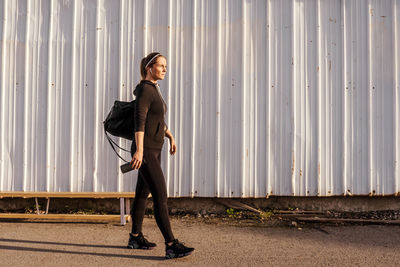 Full length of woman standing against wall