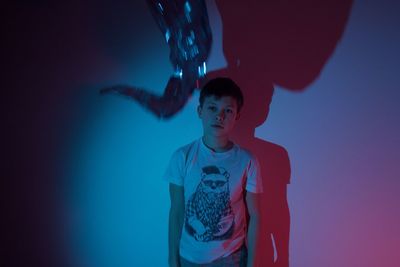 Portrait of boy standing against wall in darkroom
