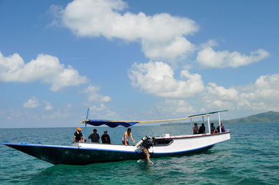 People sailing in sea against sky