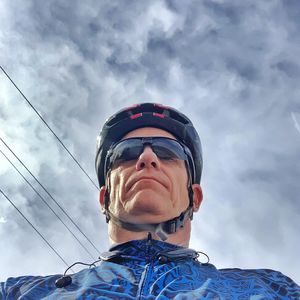 Low angle view of man wearing bicycle helmet against sky