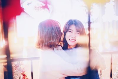 Smiling young woman looking through window