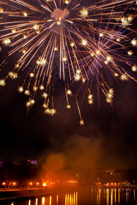 Fireworks in evening sky over river in city. holiday concept. close-up, vertical position of frame