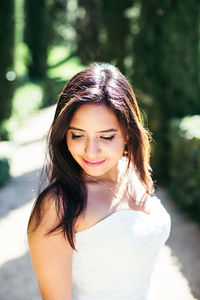 Close-up bride looking down while standing in park during sunny day