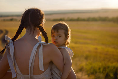 Mother and son goes to the field at sunset in a straw hat