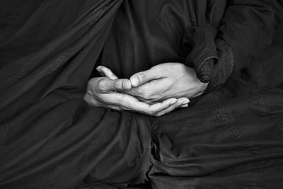 Midsection of woman praying with hands clasped