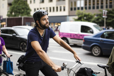 Thoughtful man riding bicycle in traffic on city street