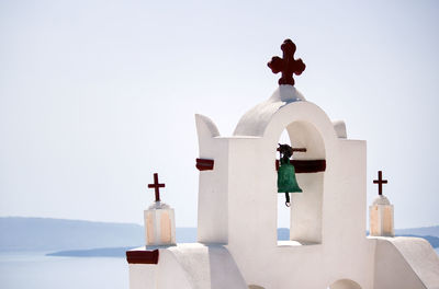 Top of a church with cross sign and bells architecture in one of cycladic island in santorini