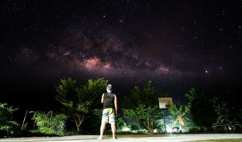 Rear view of man standing against sky at night